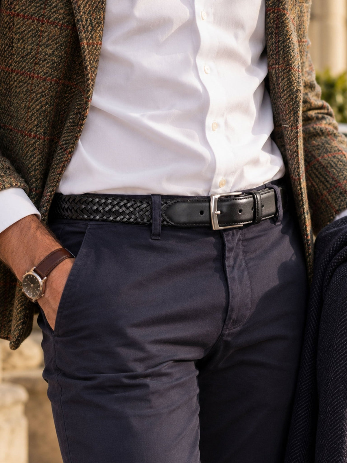 Dents men's plaited leather belt in black, worn with white shirt, navy trousers and tweed jacket