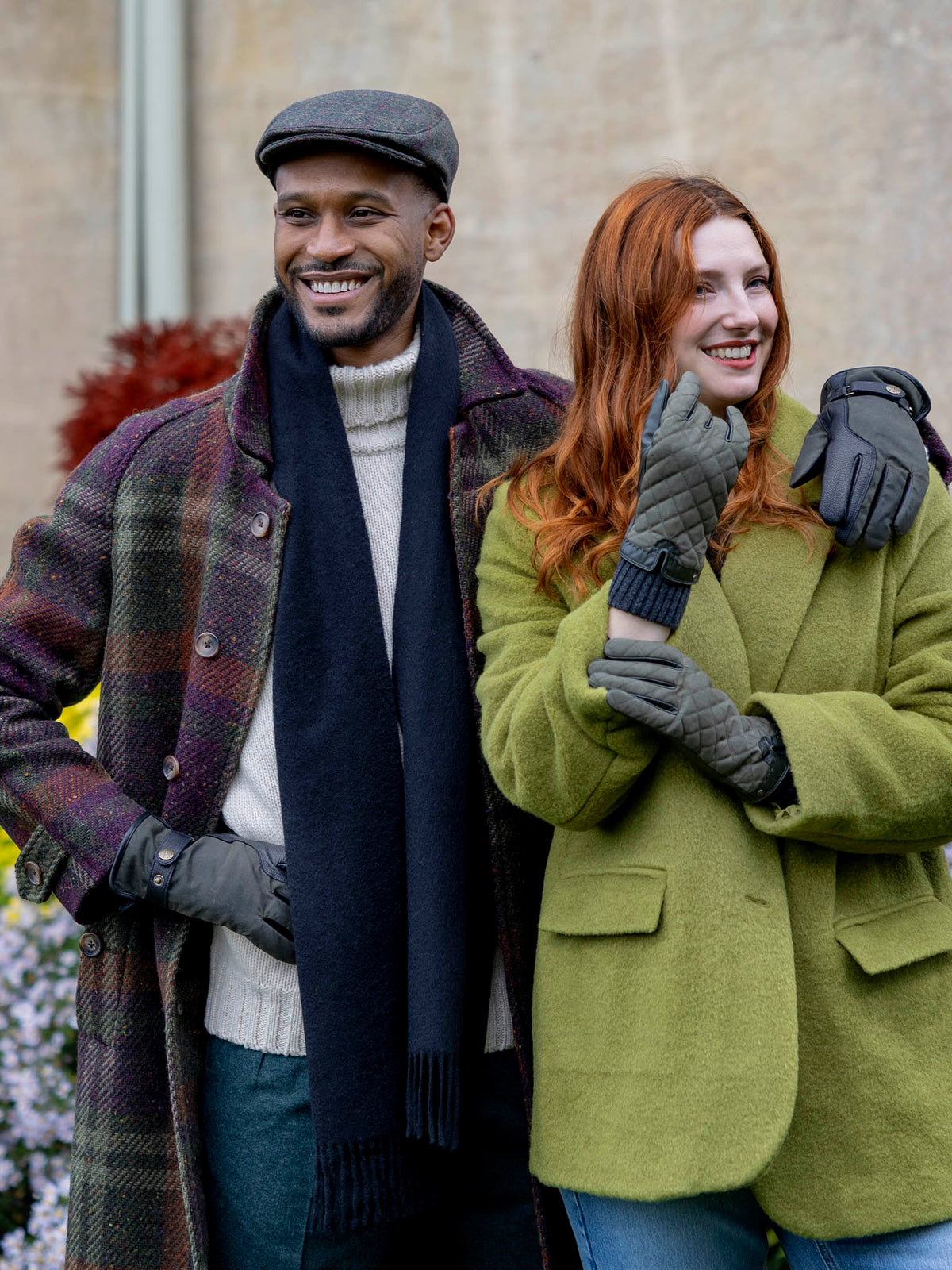 Man wearing the Dents olive windowpane check tweed flat cap with a plaid coat, outdoor lifestyle view