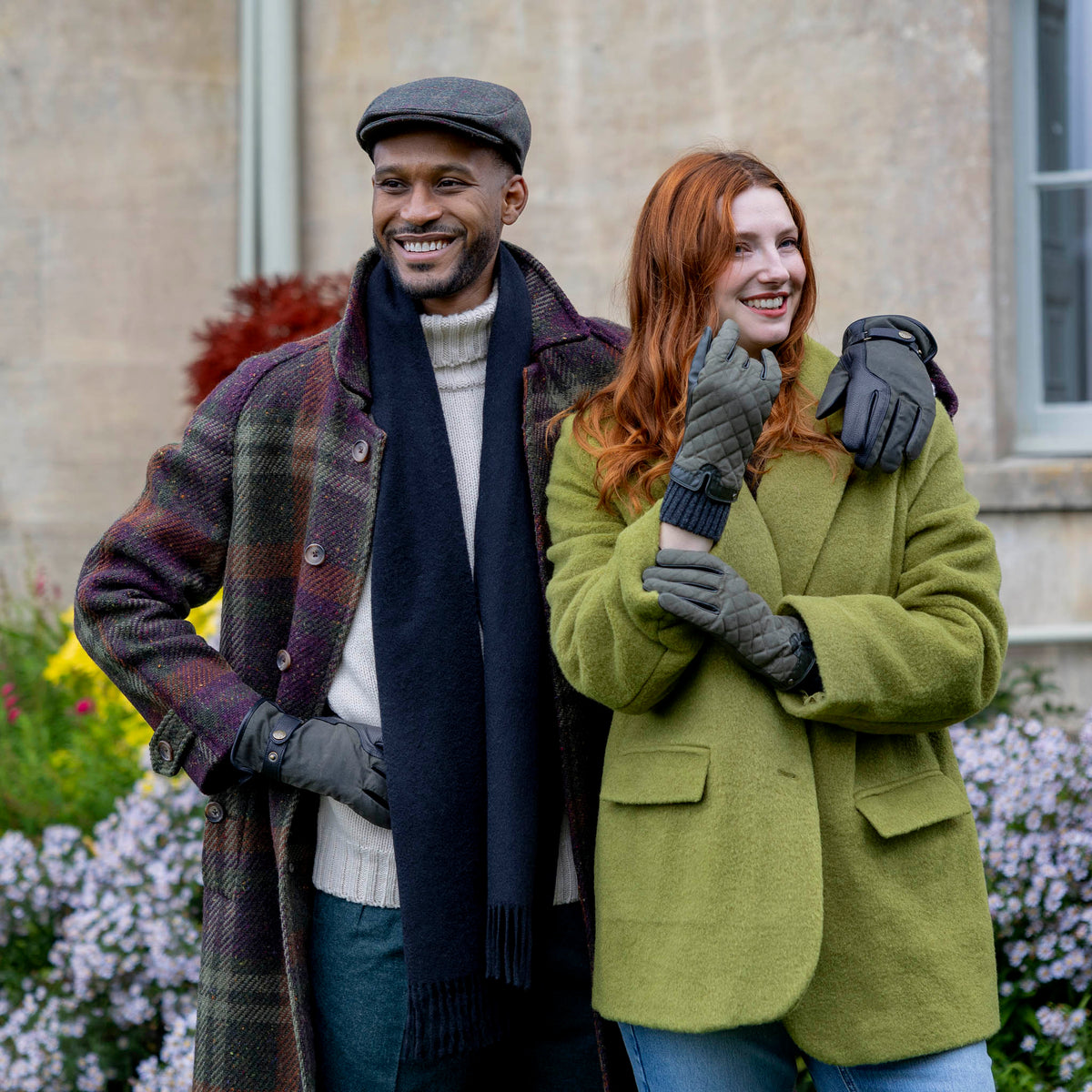 Man wearing the Dents olive windowpane check tweed flat cap with a plaid coat, outdoor lifestyle view