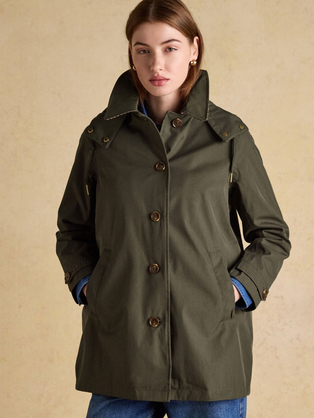 Joules Rainmore ladies waterproof button-through raincoat in green, front view worn with jeans