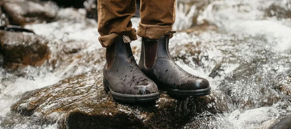 Person wearing Blundstone Chelsea boots standing in a shallow rocky stream