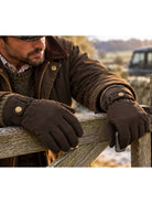 Dents men's water resistant waxed cotton gloves, worn with waxed jacket leaning on a gate