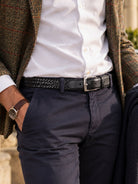 Dents men's plaited leather belt in black, worn with white shirt, navy trousers and tweed jacket