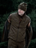 Harkila Heat men's heated gilet worn with a beanie in woodland, full-length view
