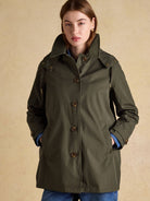 Joules Rainmore ladies waterproof button-through raincoat in green, front view worn with jeans
