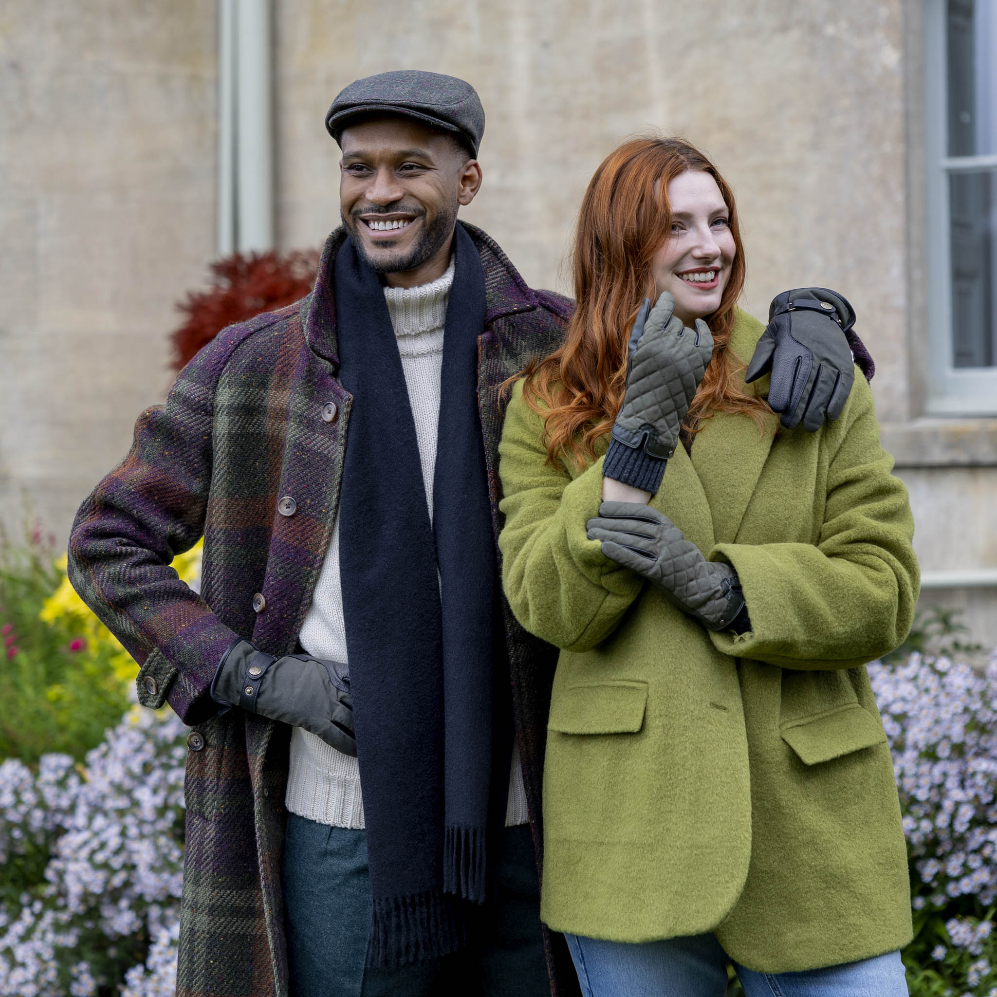 Man wearing the Dents olive windowpane check tweed flat cap with a plaid coat, outdoor lifestyle view